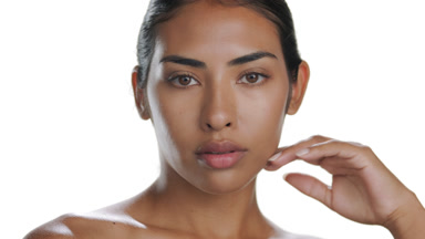 Warm-toned Latin woman touches chin, featuring nourished skin