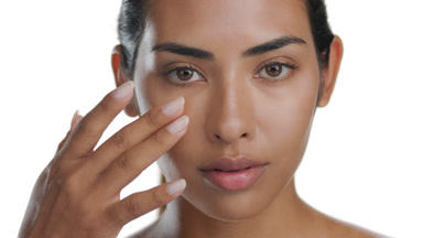 Tan beauty model strokes under eye, highlighting elastic skin