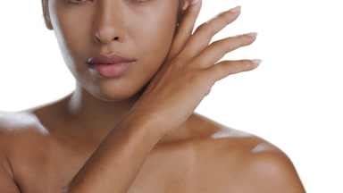 Olive-tan woman strokes jawline, chin, emphasizing balanced skin