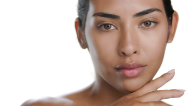 Young Latin beauty touches chin, exposing healthy, glowing skin