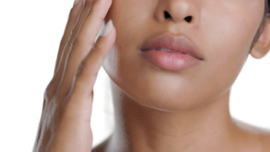 Stylish young Hispanic woman strokes cheek downward, clear skin