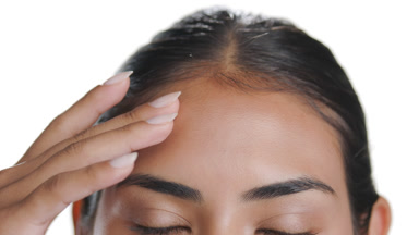 Vibrant Latin woman slides fingers down face, clear smooth skin