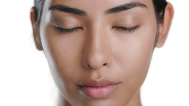 Young Latin beauty opens eyes at camera, showing healthy skin