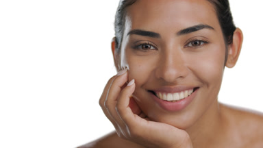 Latin model with tan skin props chin, smiles, moisturized skin
