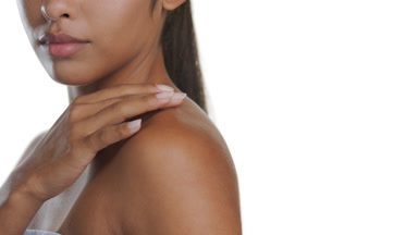 Spanish woman turns to camera, strokes shoulder, nourished skin