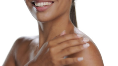 Hispanic brunette strokes shoulder, smiles, moisturized skin