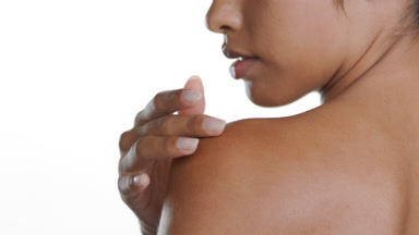 Young Latina strokes nape, shoulder, standing back to camera