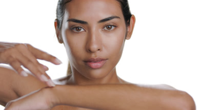 Tan young beauty model touches forearm, showing moisturized skin
