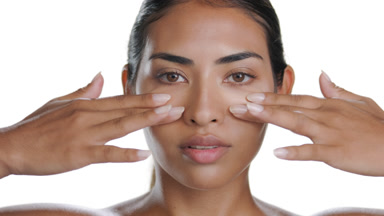 Olive-tan woman strokes under eye area, visualizing elastic skin