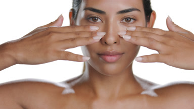 Latin brunette woman strokes under eyes, presenting firm skin