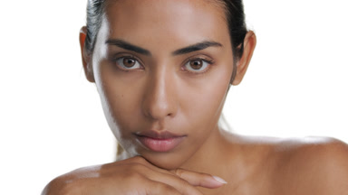 Young Latin model props chin with hand demonstrating clear skin