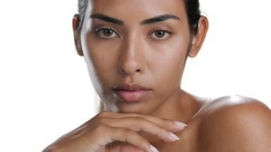 Hispanic beauty props chin with hand, displaying balanced skin