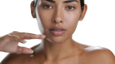 Dark-eyed brunette Latin woman touches chin, protected skin