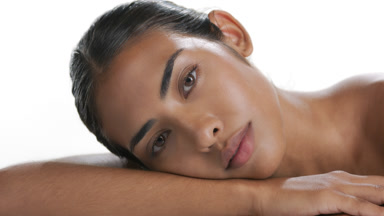 Latin brunette leans head on forearm exhibiting matte skin