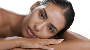 Vibrant woman lifts head, strokes cheek, shows moisturized skin