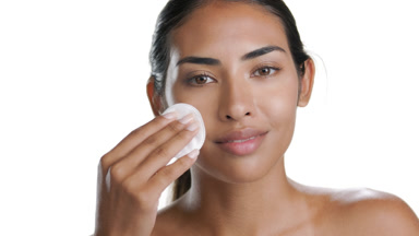Mid-brown skinned Latin woman uses cotton pad reveal clear skin