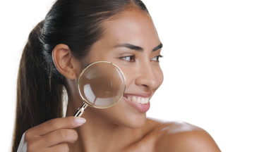 Young beauty model with magnifying glass highlights pure skin