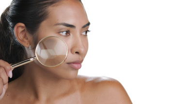 Young Latin woman magnifies face showing smooth light brown skin