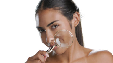 Youthful Latin model smiles magnifying glass promotes clear skin