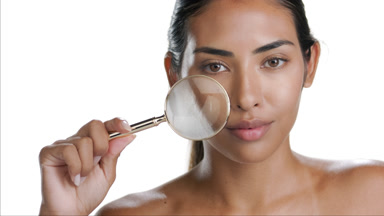 Spanish young woman zooms face skin with magnifying glass