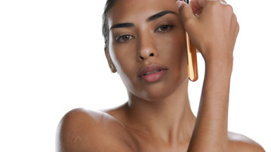 Young Latina moves test tube with orange liquid along face