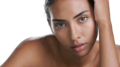 Young warm-complexioned woman touches forearm, moisturized skin