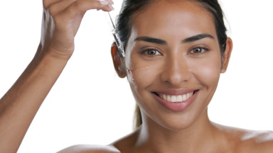 Young Latin beauty applies serum, hand over head