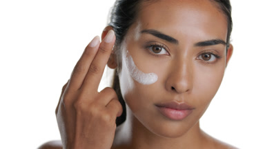 Hispanic beauty applies face cream on cheek with finger