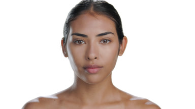 Mid brown-skinned Latin woman lifts gaze, clear skin