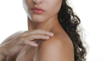 Fair Latin model strokes shoulder, displaying nourished skin