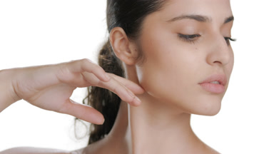 Hispanic woman with fair skin touches chin, strokes jaw