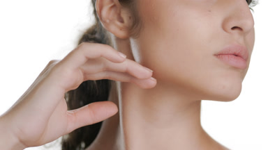 Spanish woman strokes jawline looking aside showing clear skin
