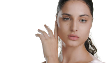 Young fair-skinned Latin woman strokes cheek, chin