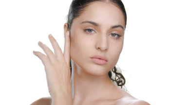 Young Latina with fair skin strokes cheek, moisturized skin