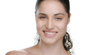 Spanish woman smiles at camera, illustrates healthy skin