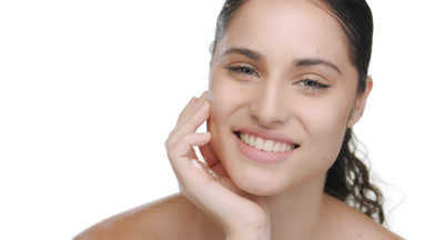 Model with green eyes props chin, smiles, highlighting pure skin