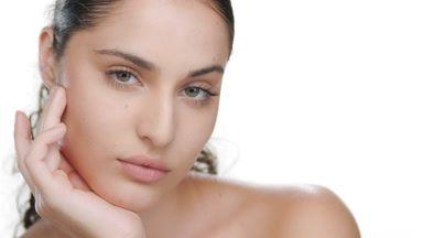 Curly fair Latina props chin, visualizes moisturized skin