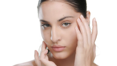 Light-skinned curly Latina touches face, presenting smooth skin