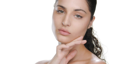 Curly Latina touches chin demonstrating nourished skin