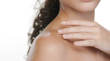 Curly-haired Latina strokes collar bones exhibits nourished skin