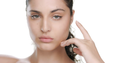 Young Latina with fair skin props chin, strokes cheek