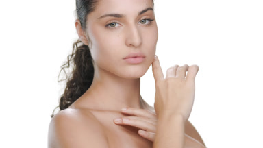 Fair Latin woman touches chin, clavicles, showing smooth skin
