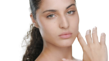 Young Latin beauty strokes chin and jawline, firm skin