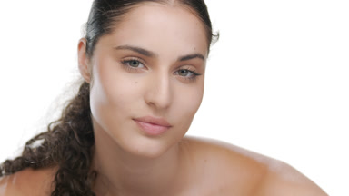 Youthful Latin model lifts head off forearm, rejuvenated skin