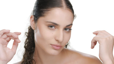 Hispanic brunette touches chin with both hands, firm skin shown