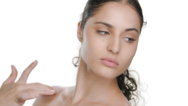 Fair Latin model strokes jawline, looks over shoulder, soft skin