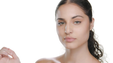 Hispanic woman with fair skin touches cheek, elastic skin shown