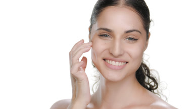 Spanish woman with fair skin touches cheek, smiles, firm skin