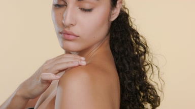 Young Latina with fair skin strokes shoulder, looks over