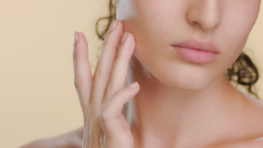 Fair-skinned Latin woman strokes cheek upwards, soft skin
